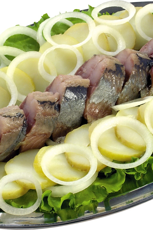 Сельдь с вареным картофелем, луком и листьями салата на белом фоне