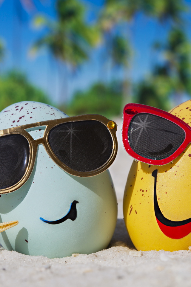 Два яйца в солнечных очках на морском песке летом