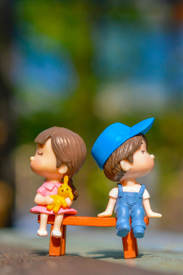 Две маленькие игрушки мальчик и девочка на лавке