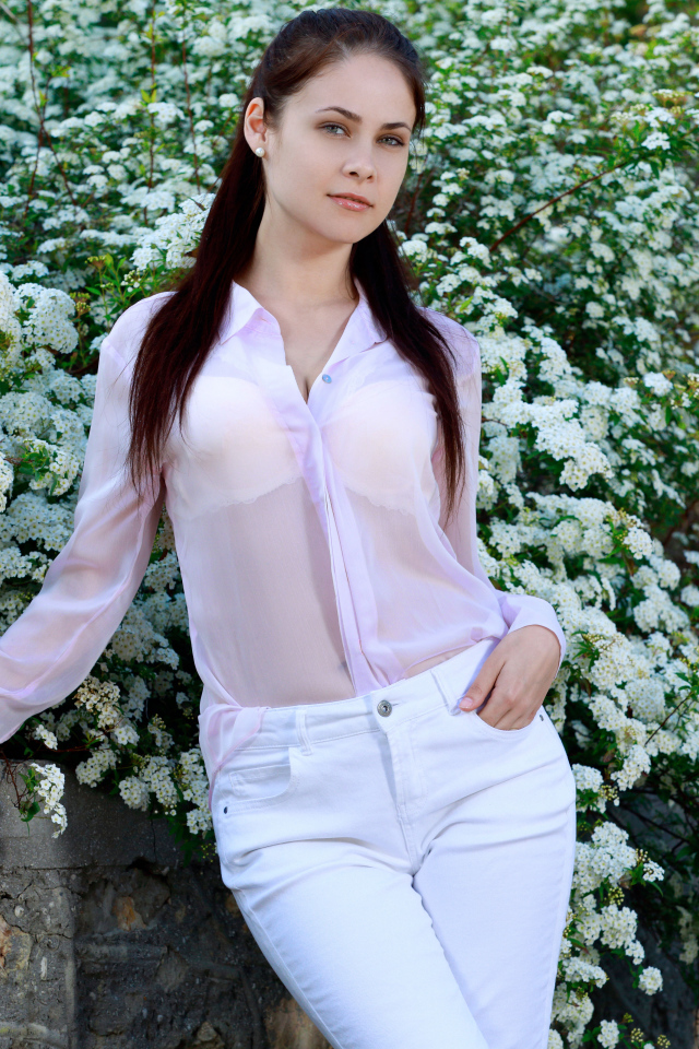 Красивая девушка стоит на фоне цветущего куста