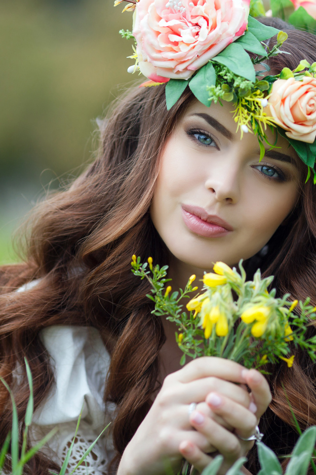Красивая девушка с венком на голове лежит на траве