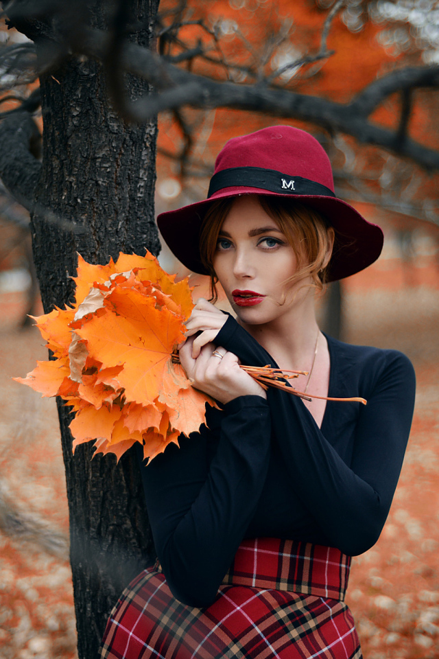 Девушка стоит у дереве с желтыми листьями осенью