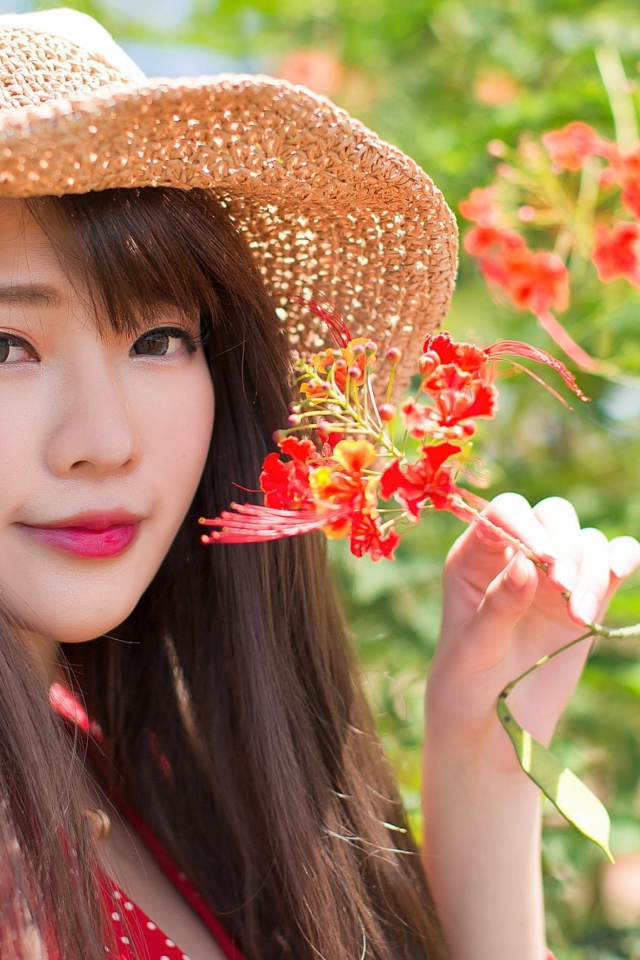 Девушка азиатка в шляпе с красным цветком