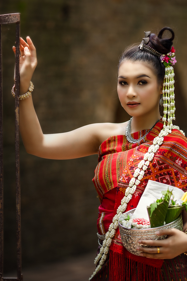 Девушка азиатка в костюме стоит у железных ворот