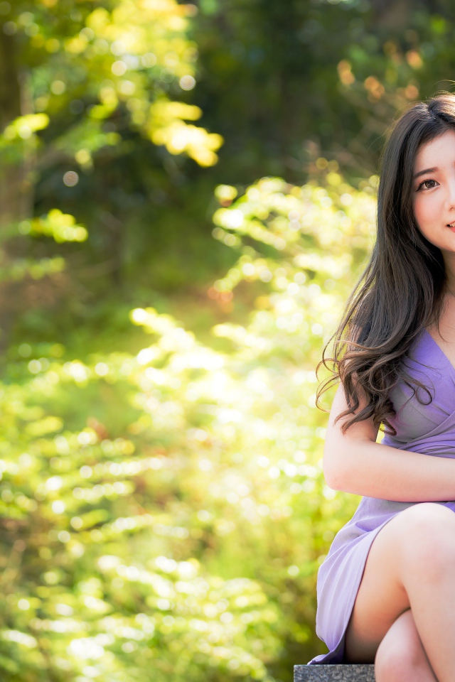 Молодая девушка азиатка сидит на лавке в парке