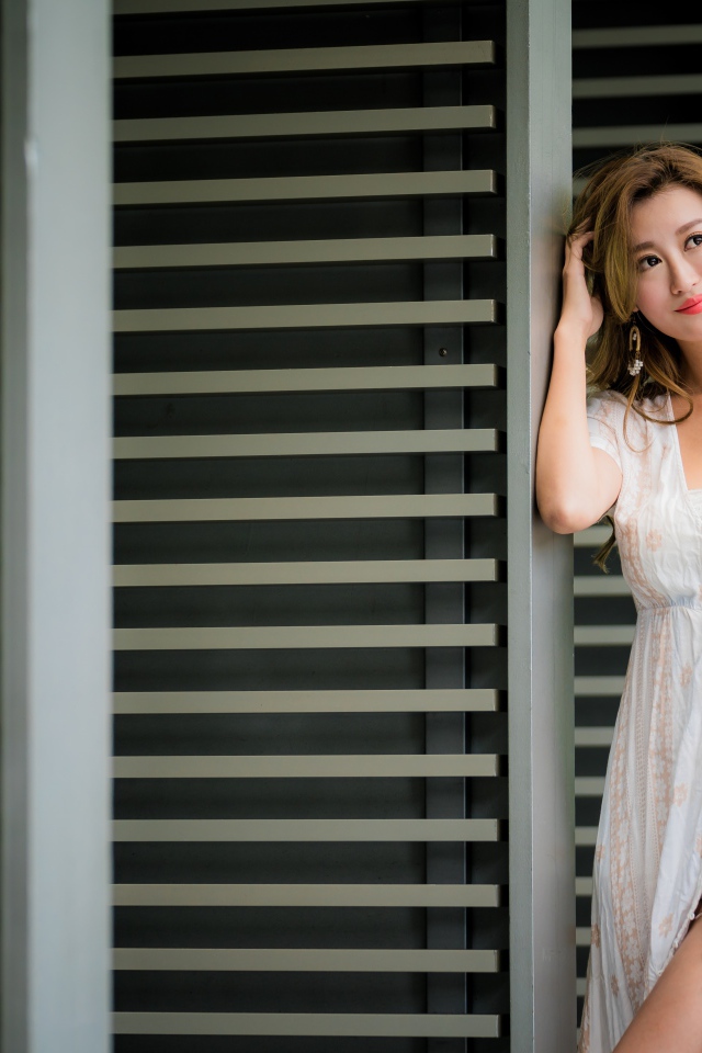 Красивая девушка азиатка в платье стоит у дверей