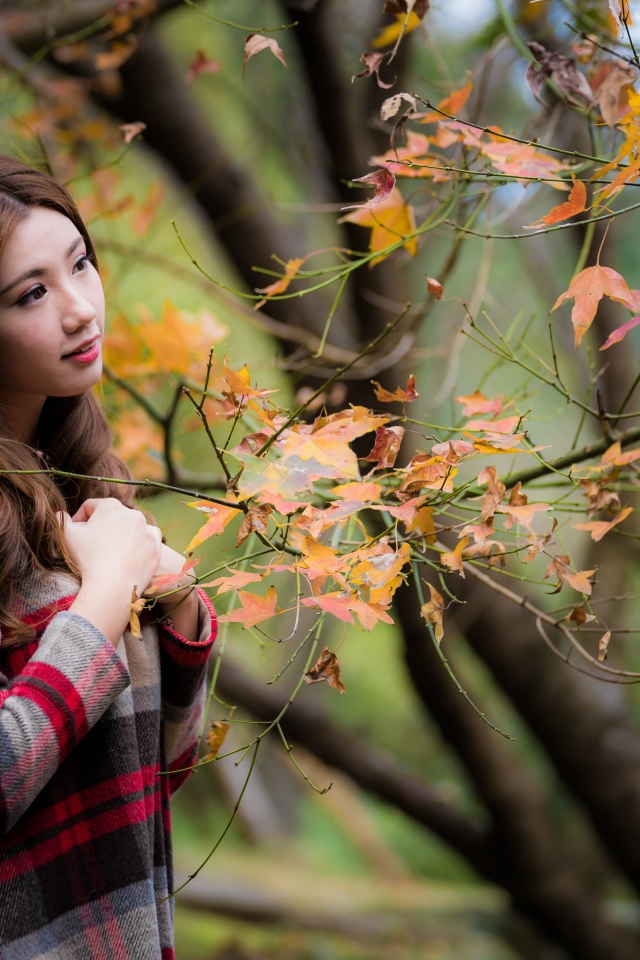 Красивая азиатка стоит у дерева