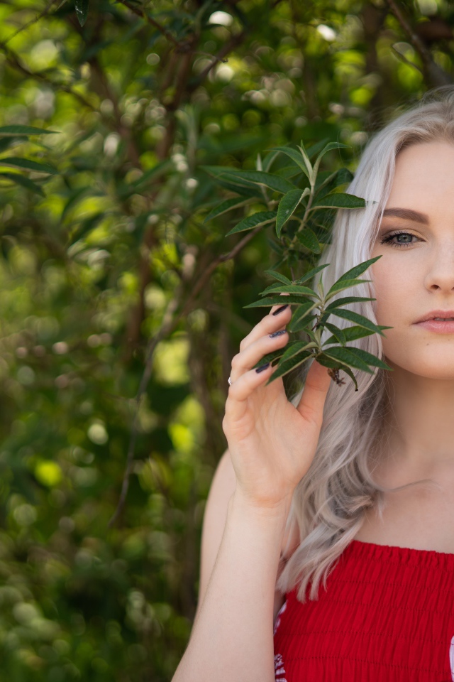 Красивая блондинка стоит у дерева 