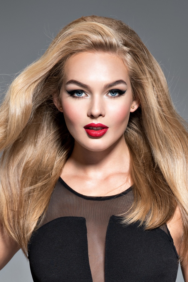 Красивая голубоглазая блондинка в черном платье на сером фоне