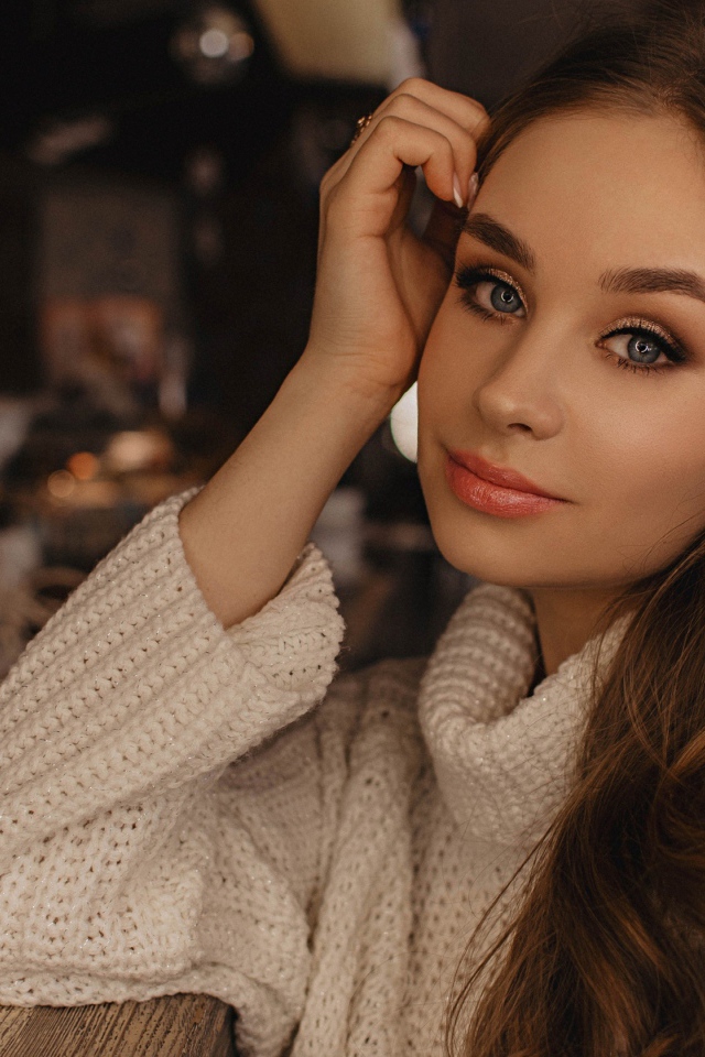 Красивая голубоглазая девушка в белом свитере в кафе