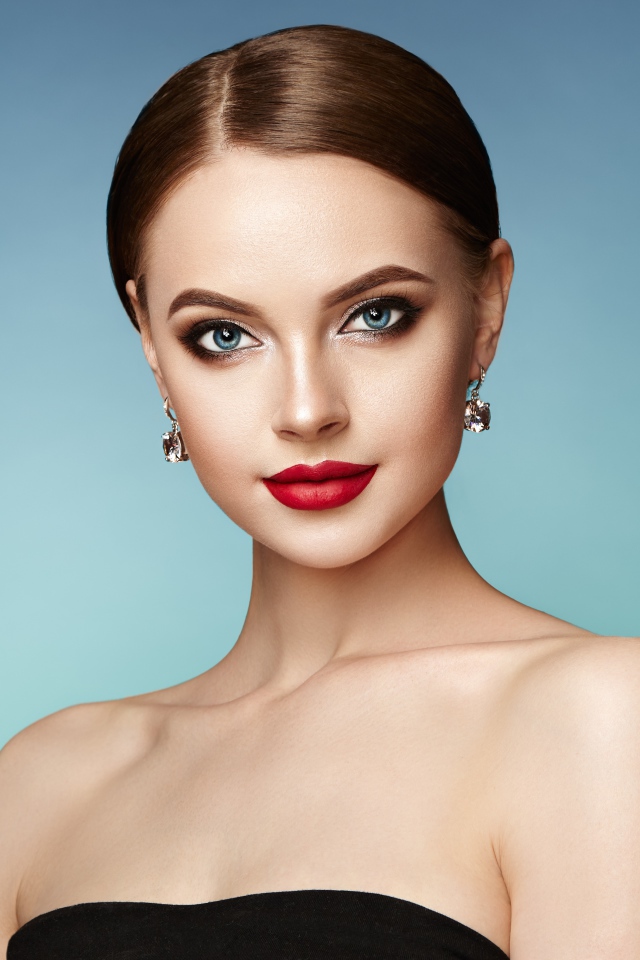 Красивая голубоглазая девушка с накрашенными губами и серьгами в ушах