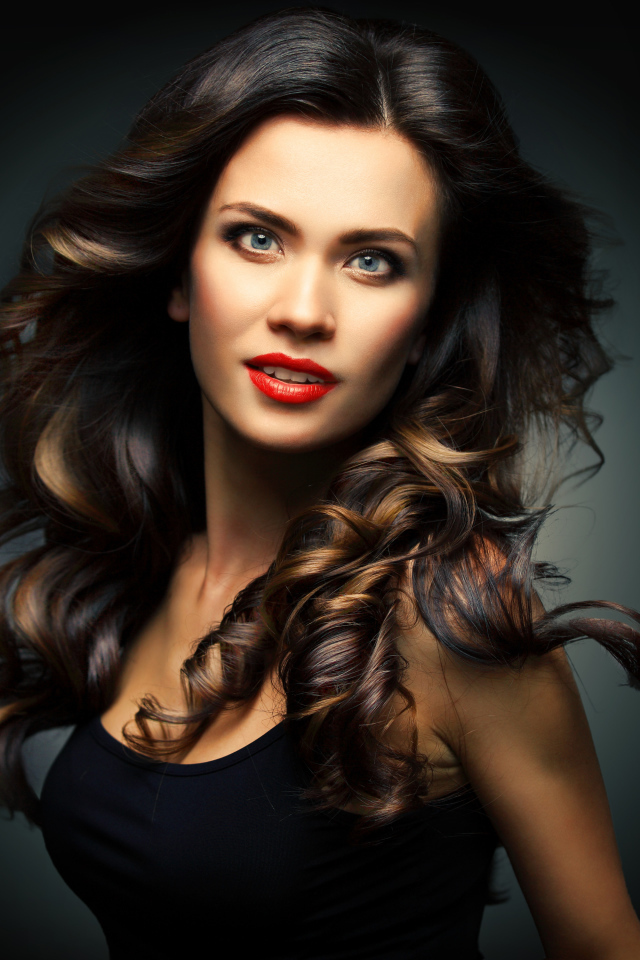 Красивая яркая девушка с длинными волосами на сером фоне