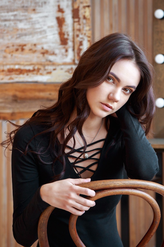 Красивая кареглазая девушка сидит на стуле