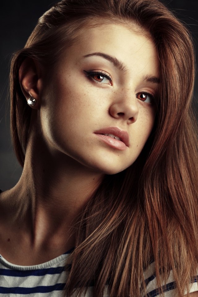 Красивая кареглазая девушка с русыми волосами на сером фоне