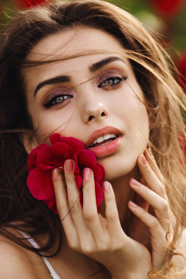 Красивая девушка шатенка с цветком у лица