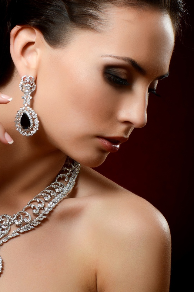 Красивая девушка шатенка с дорогими украшениями на шее и ушах
