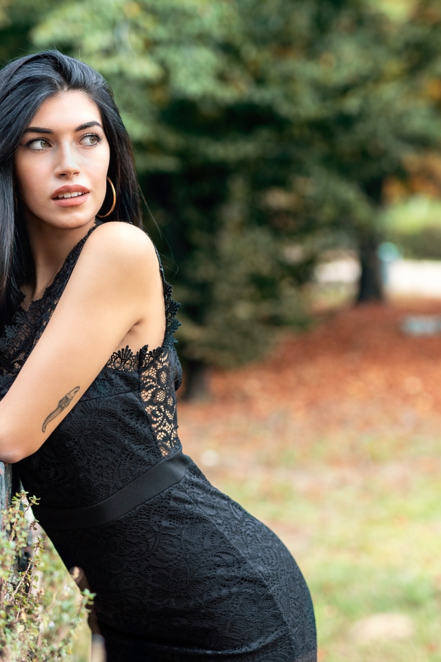 Красивая брюнетка в черном платье в парке