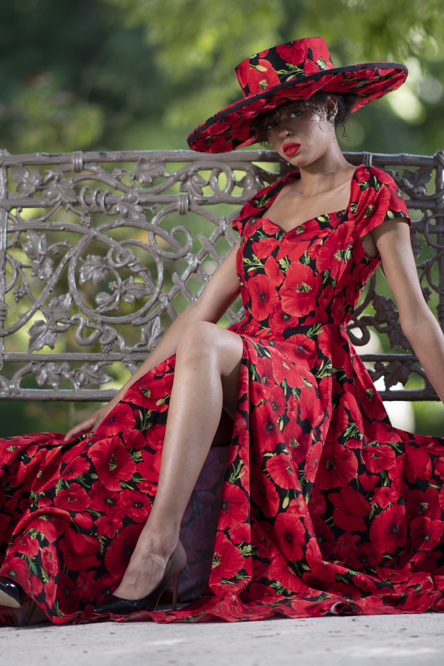 Красивая темнокожая девушка в красном платье сидит на лавке