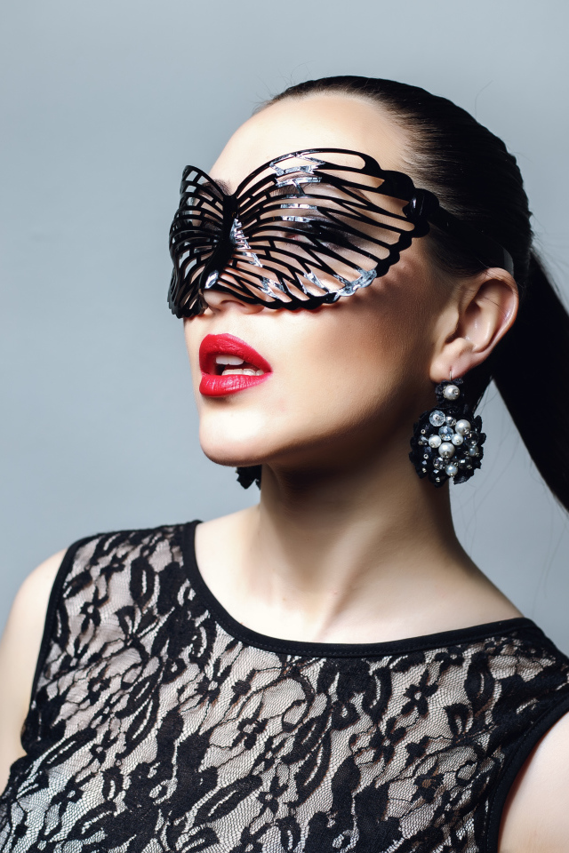 Красивая модная девушка в черной маске на сером фоне