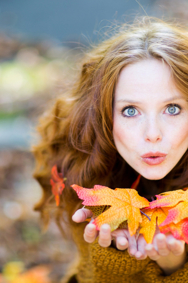Красивая девушка сдувает листья с ладоней