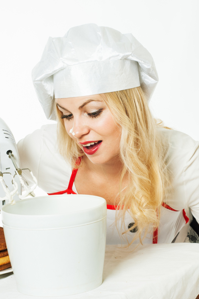 Красивая девушка повар взбивает крем для торта миксером