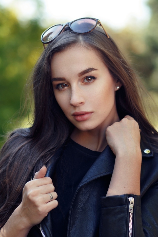 Красивая девушка в черной куртке с очками на голове