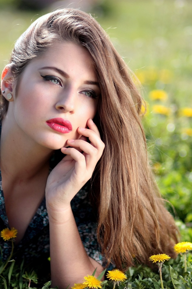 Красивая девушка в платье лежит на траве с одуванчиками