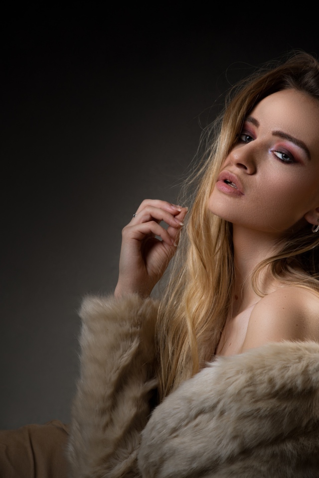 Красивая девушка в шубе на сером фоне