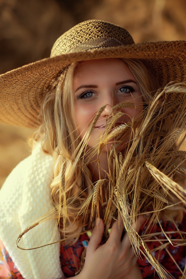 Красивая девушка в шляпе с колосьями в руке