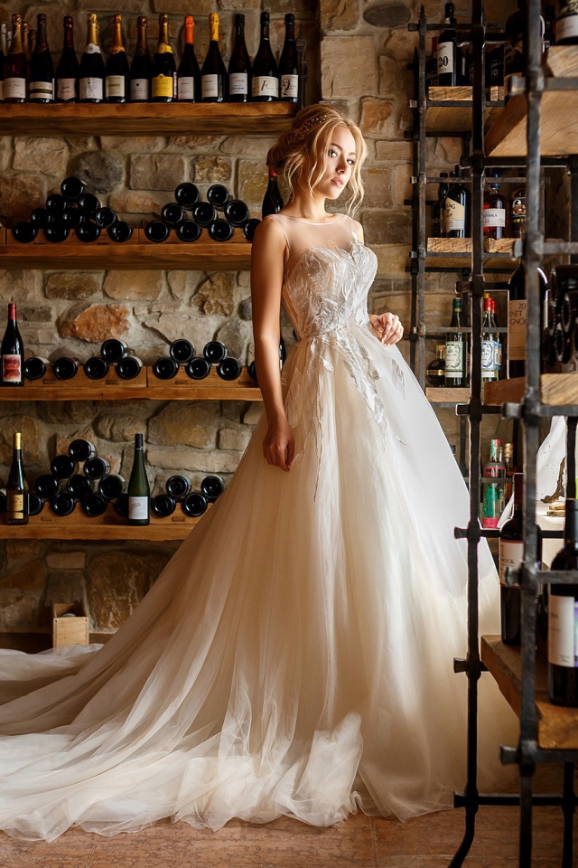 Красивая девушка в пышном свадебном платье в винном погребе