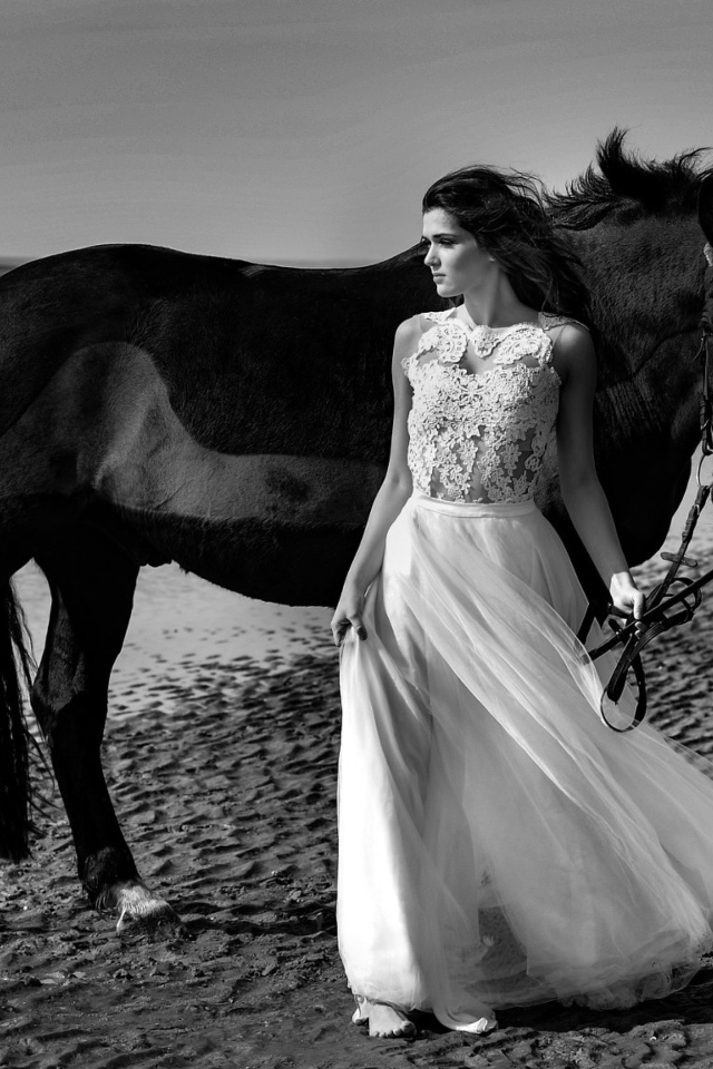 Красивая девушка в свадебном платье с лошадью на берегу моря