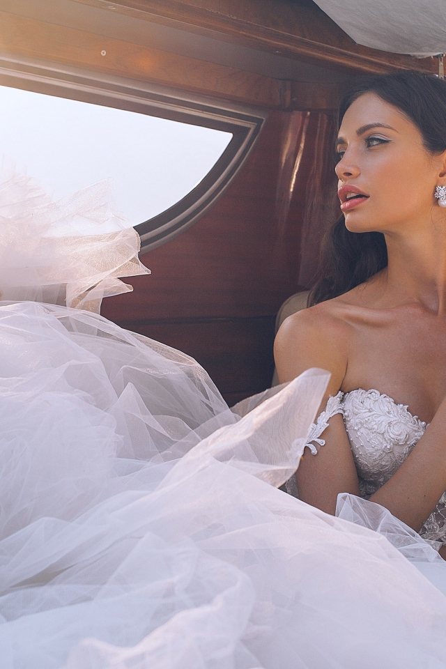 Красивая девушка в белом свадебном платье в машине