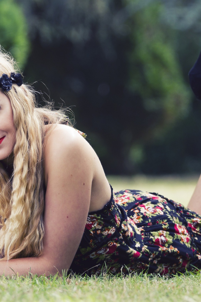 Красивая девушка в черных туфлях лежит на зеленой траве