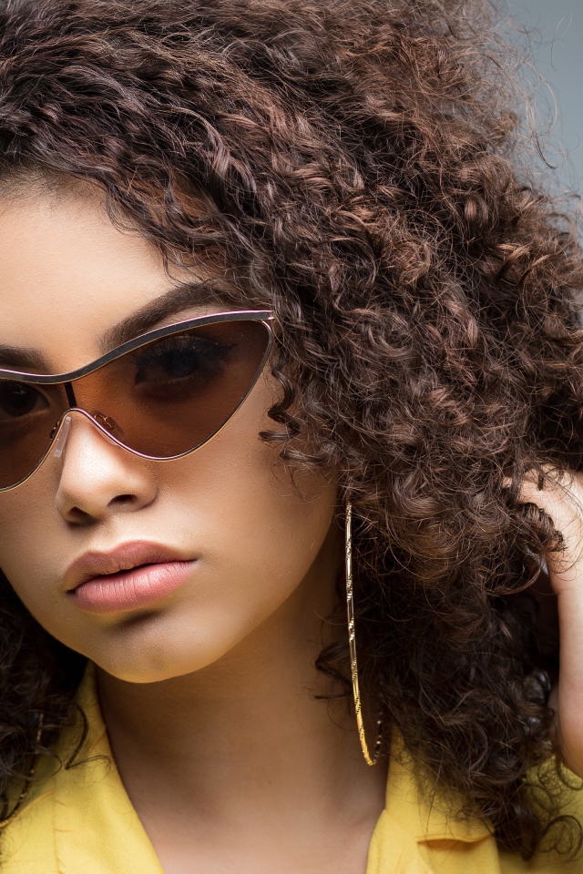 Красивая девушка в солнечных очках на сером фоне