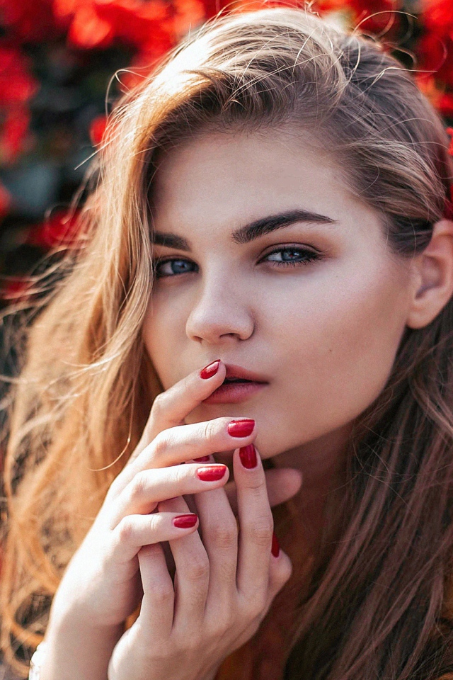 Красивая девушка на фоне красных цветов