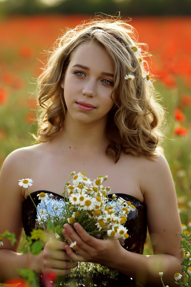 Красивая девушка с букетом ромашек на поле с маками