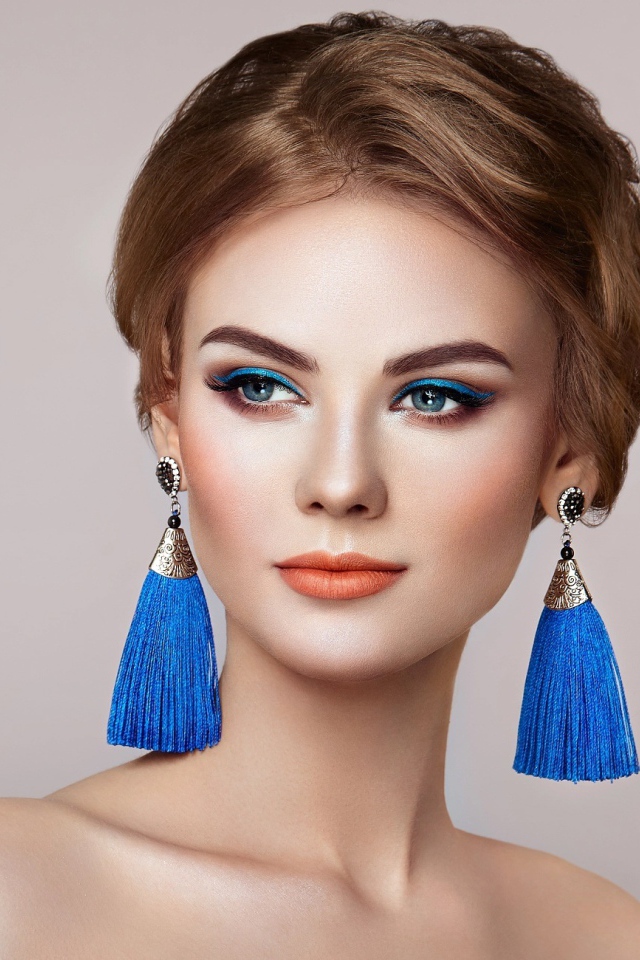 Красивая девушка с синими сережками на сером фоне