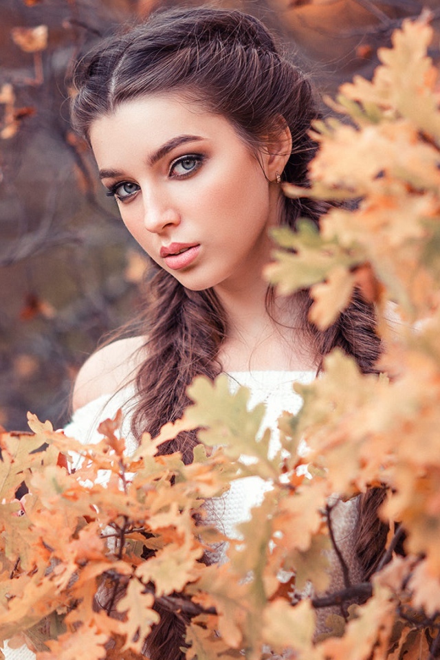 Красивая девушка с косами на фоне желтых листьев 