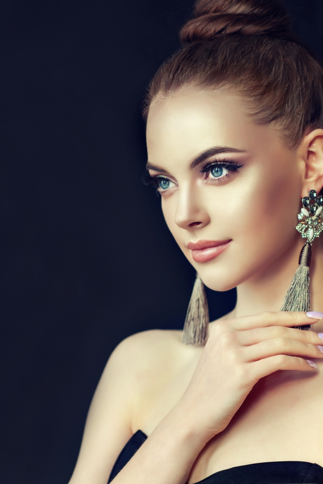 Красивая девушка с серьгами на черном фоне