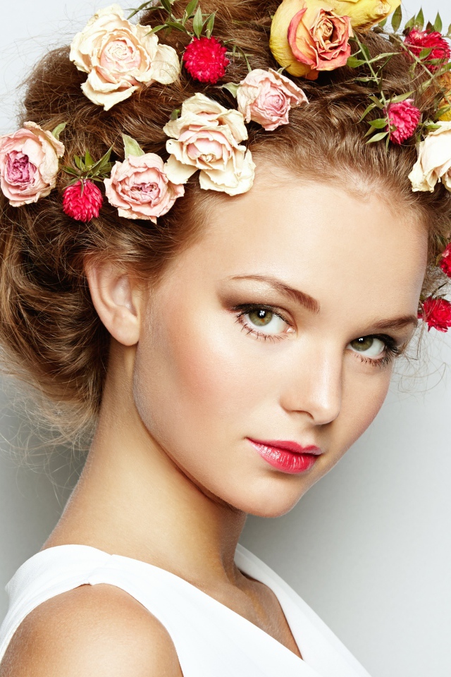 Красивая девушка с цветами в волосах на сером фоне