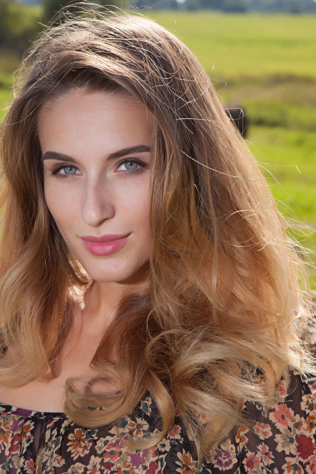 Красивая девушка с серыми глазами стоит у сена