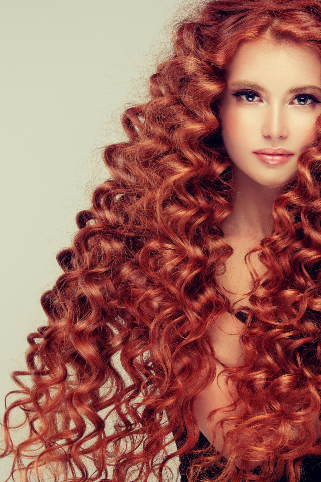 Красивая девушка с длинными рыжими волосами на сером фоне