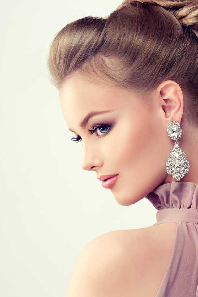 Красивая девушка с макияжем и прической на сером фоне