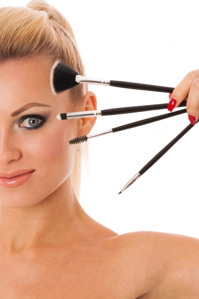 Красивая девушка с кистями для макияжа на белом фоне