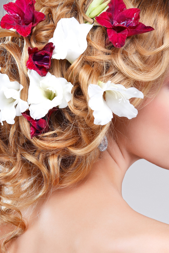 Красивая девушка с цветами петунии в волосах на сером фоне