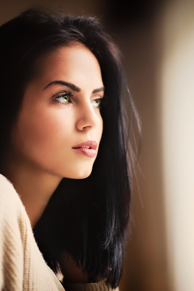 Красивая девушка зеленоглазая смотрит в окно 