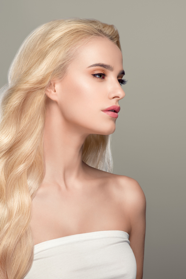 Красивая длинноволосая девушка блондинка на сером фоне