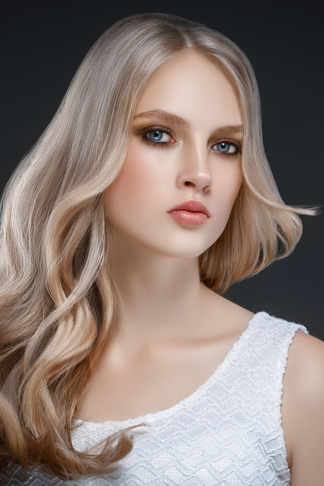 Красивая длинноволосая блондинка с голубыми глазами на сером фоне