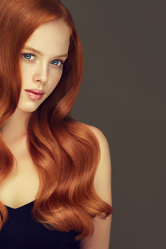 Красивая рыжеволосая голубоглазая девушка на сером фоне