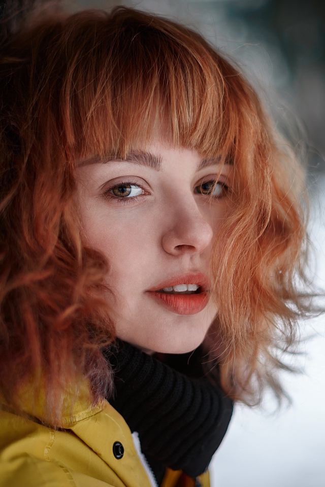 Красивая рыжеволосая девушка стоит у дерева зимой